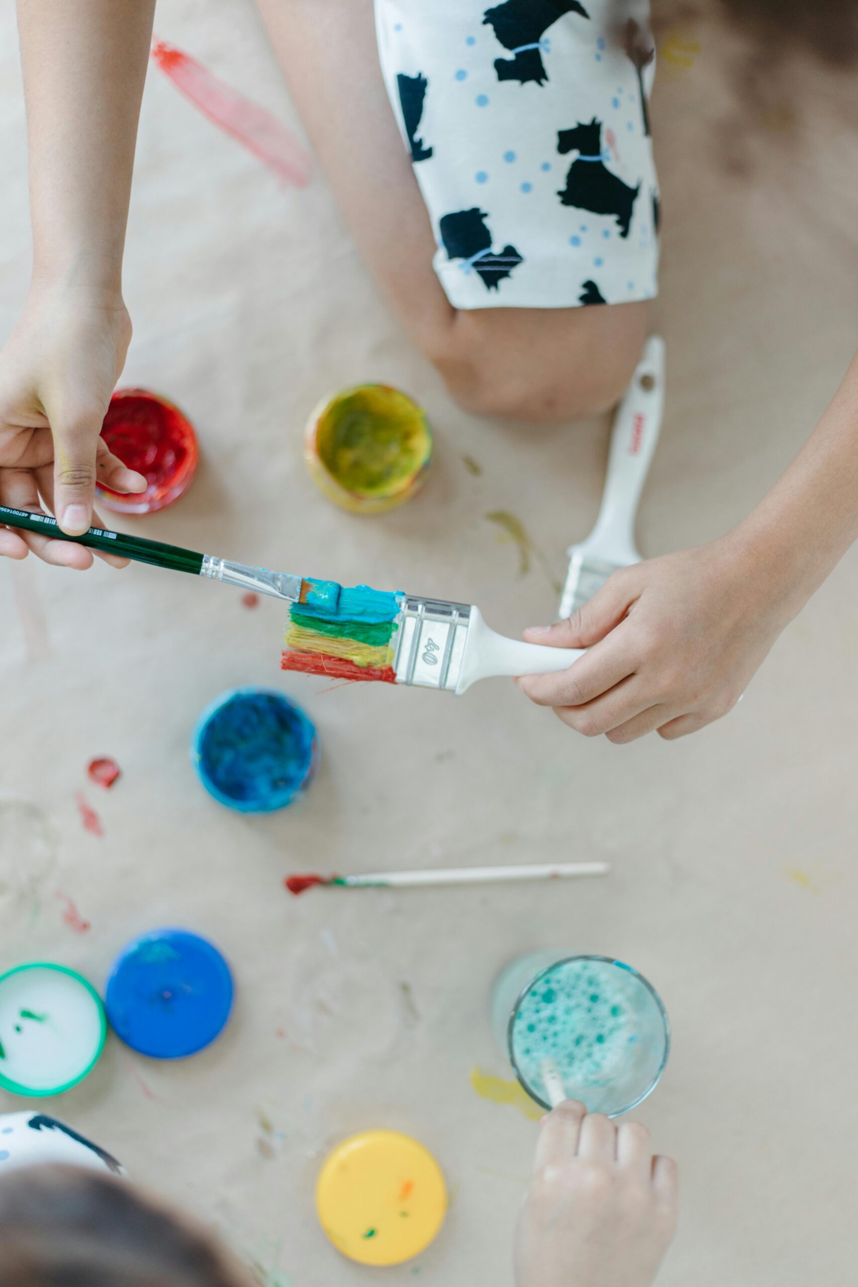 pexels-photo-6966348-6966348 Top view of children using paintbrushes and watercolors in a creative art session.